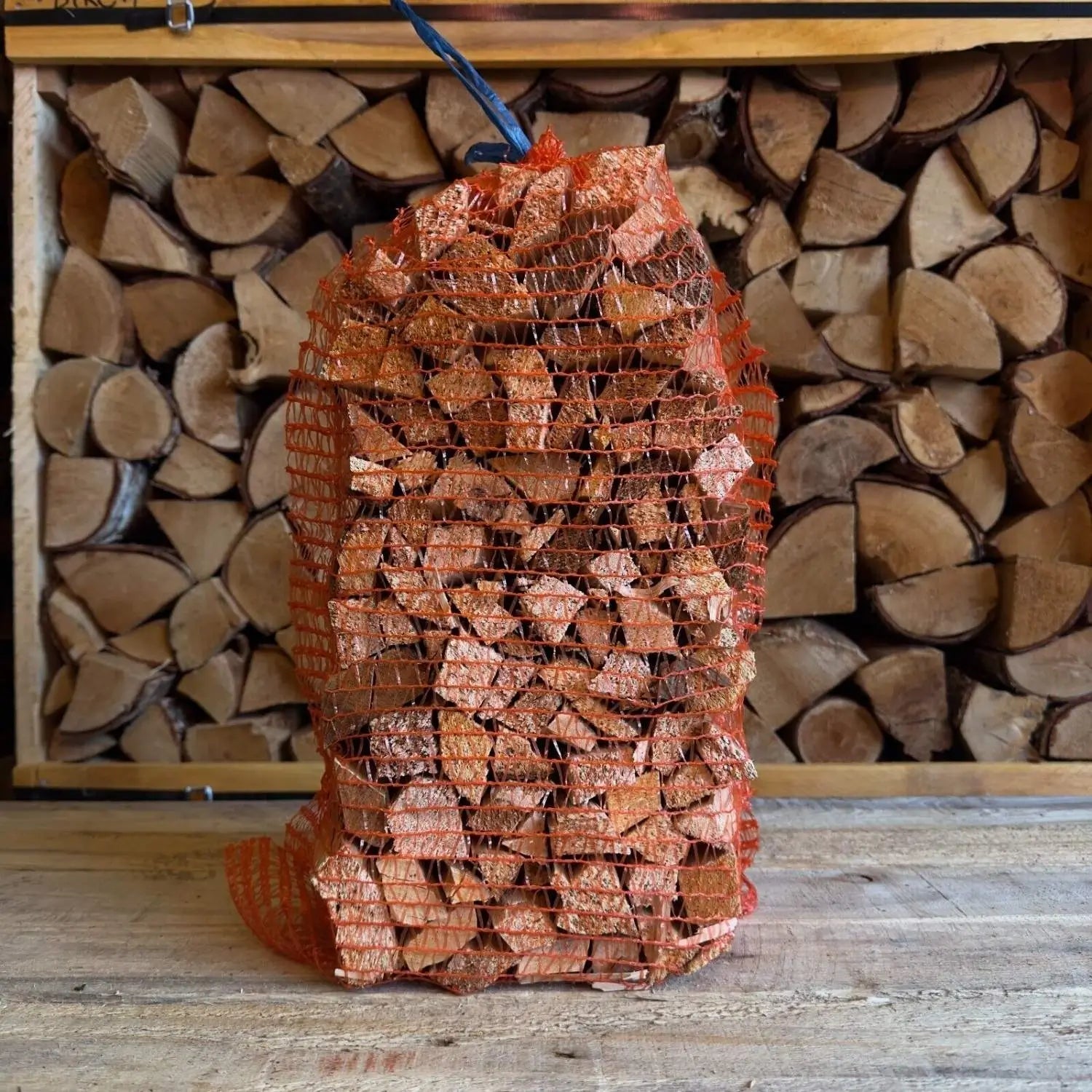 Bag of firewood in front of stacked logs