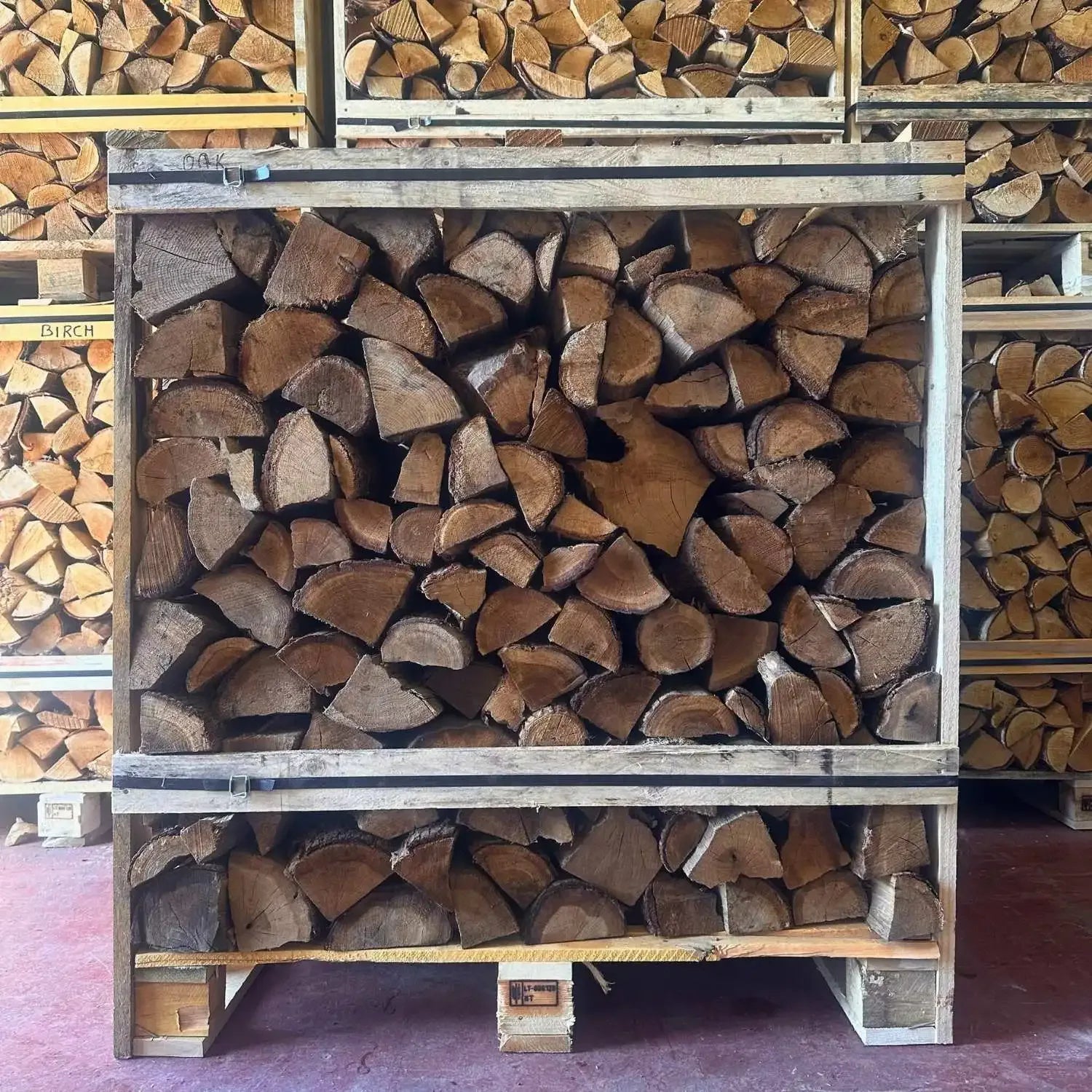 Stack of chopped wood on a wooden pallet with more wood stacked in the background.