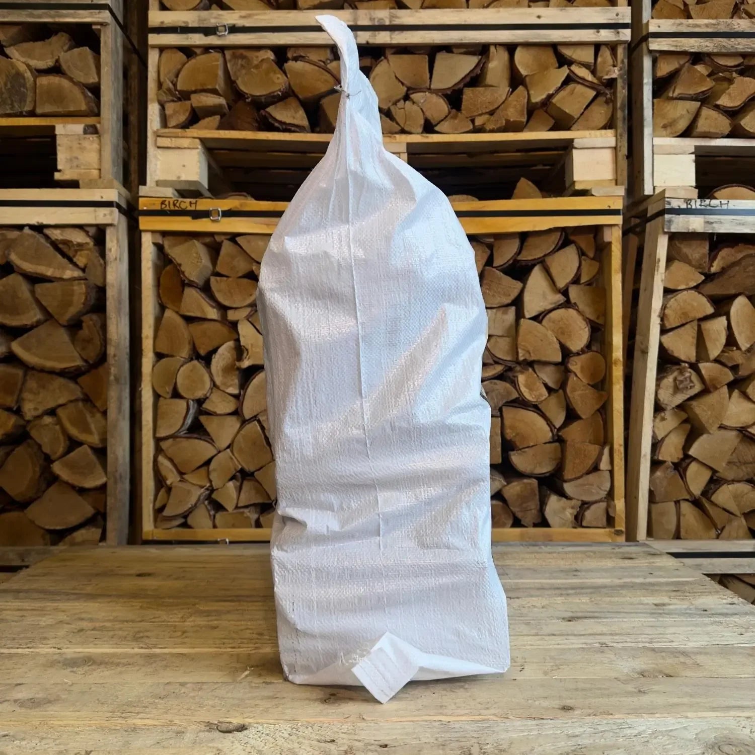 White firewood bag in front of stacked firewood logs