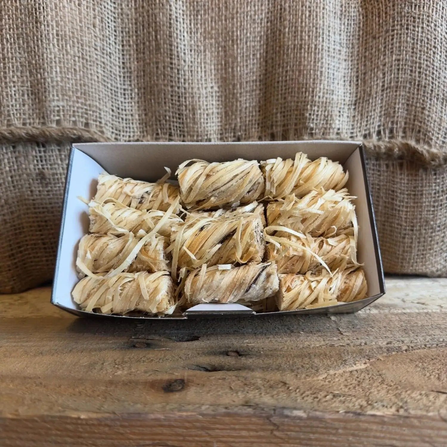 Box of wrapped items on a wooden surface with burlap background