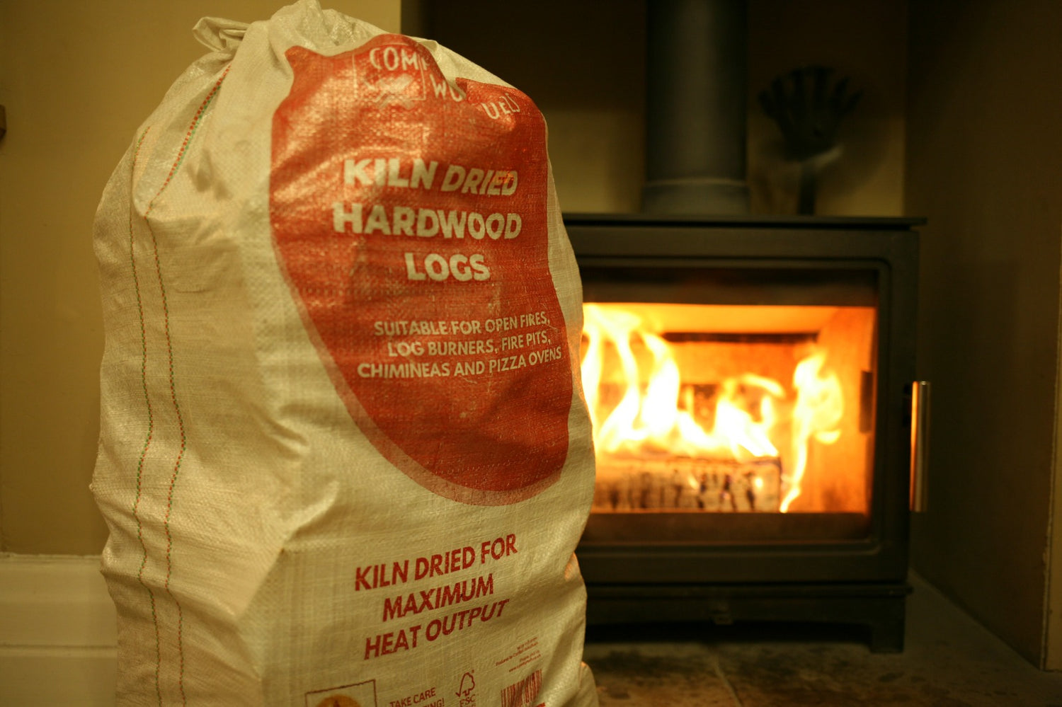 Mortimers Fuels Alder Maxi Bag of kiln-dried logs in front of a cozy fireplace, perfect for home heating