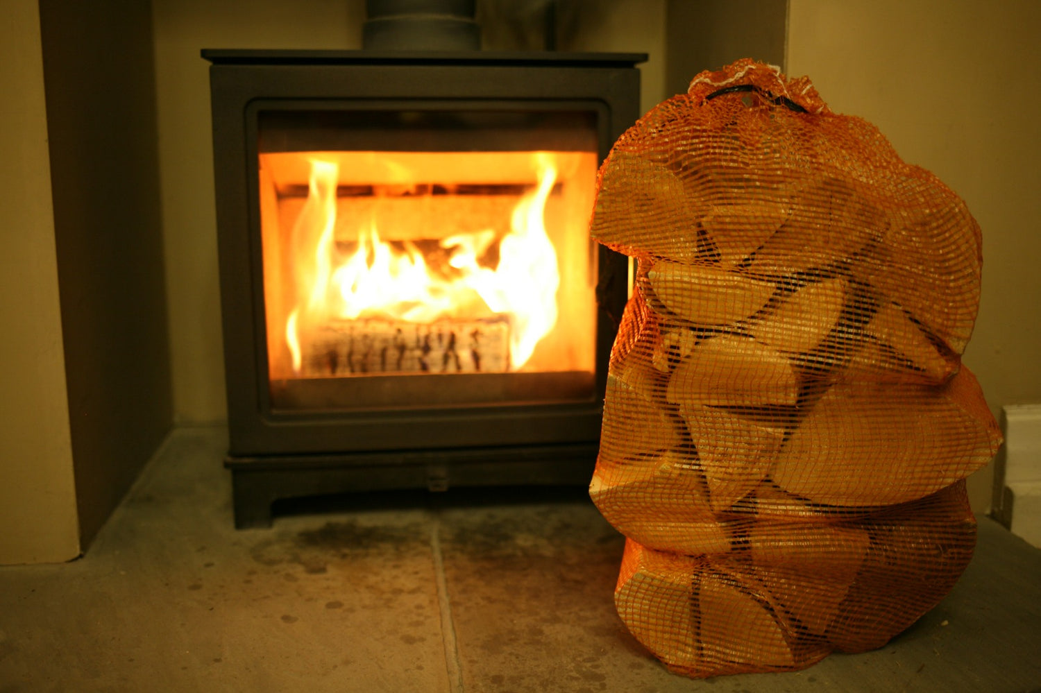 Mortimers Fuels 40L Birch Net of kiln-dried logs in front of a cozy fireplace, ready for easy ordering and delivery.